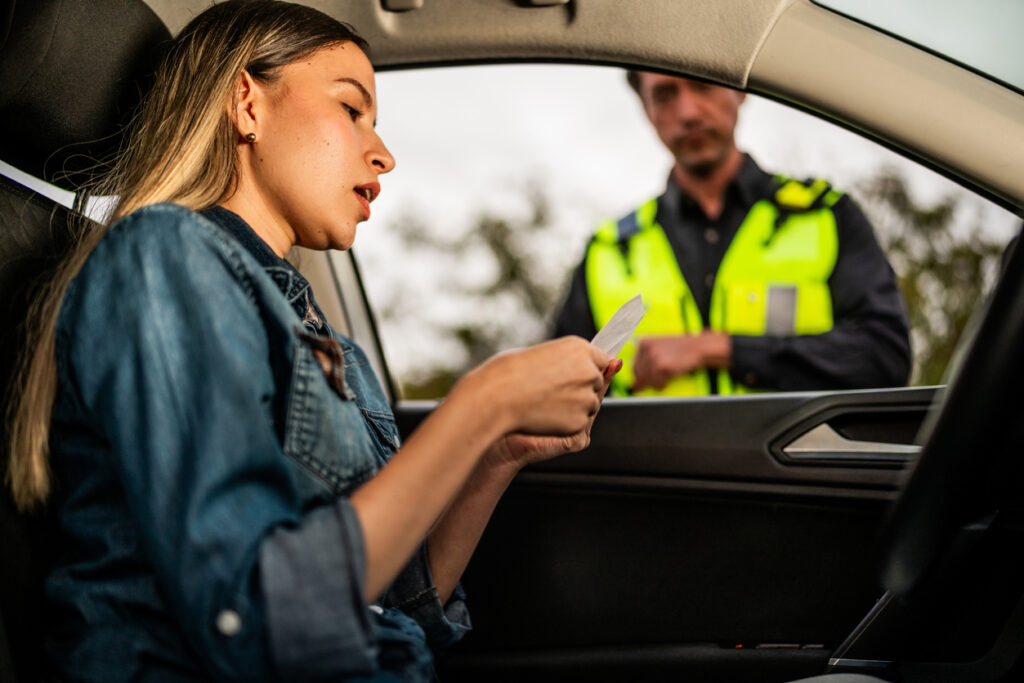 Young woman receiving a traffic ticket from a traffic cop