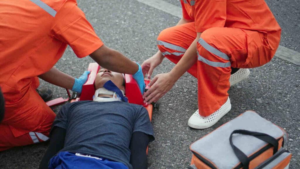Paramedics assisting an injured motorcyclist on the road after a crash in Missouri, highlighting the risks of internal injuries for riders.