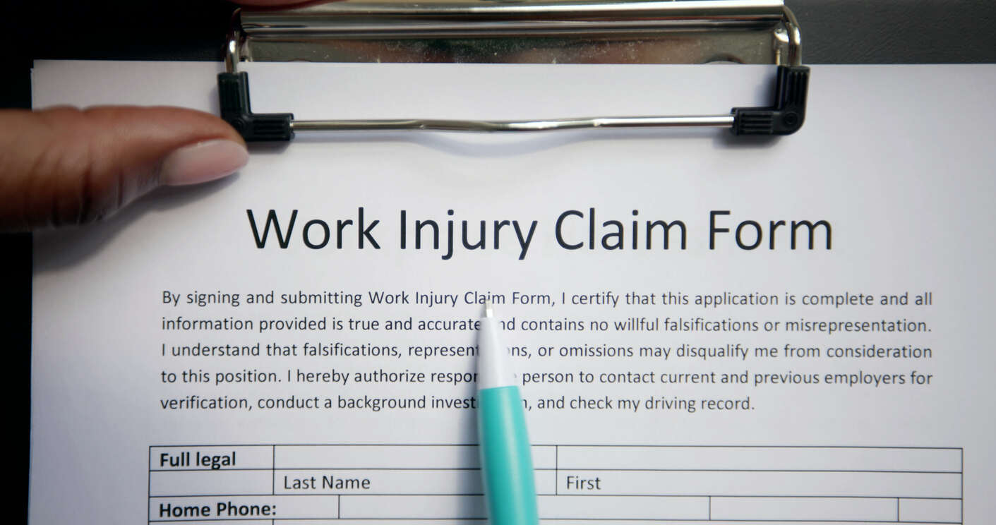 A hand with a pen over a work injury claim document, symbolizing the need for legal guidance in filing a workers' compensation claim in Missouri.
